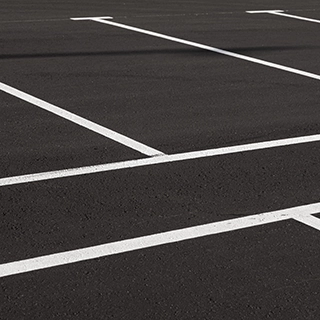 KSW An empty parking lot with white painted lines marking parking spaces on a dark asphalt surface. Denver Metro