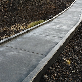 KSW A narrow, elevated concrete path with edges stretches through a rocky, barren landscape. Denver Metro